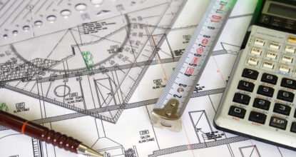 plans of house construction with calculator and tape measure